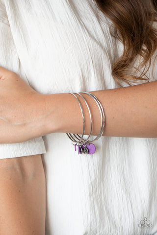 Prairie Plains - Purple Bracelet - Paparazzi Accessories Infused with mismatched silver floral charms and vivacious purple stone discs, a stack of hammered silver bangles slides along the wrist for a colorful earthy look.  Sold as one individual bracelet.  New Kit