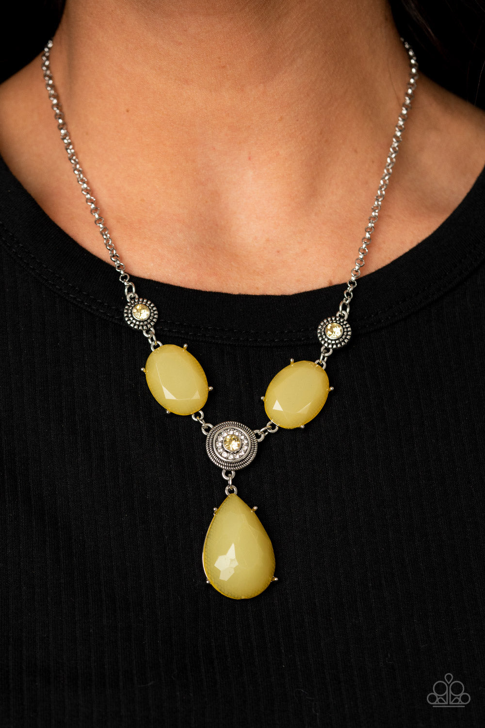 Heirloom Hideaway - Yellow Necklace - Paparazzi Accessories A collection of yellow and white rhinestone dotted silver frames link with a pair of dewy yellow oval gems below the collar. A dramatically oversized dewy yellow teardrop drips from the center, creating a glamorous pendant. Features an adjustable clasp closure.  Sold as one individual necklace. Includes one pair of matching earrings.  New Kit