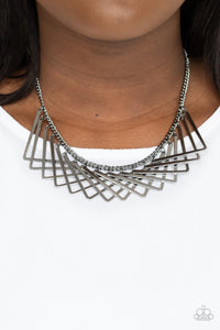 Metro Mirage - Black Necklace - Paparazzi Accessories A shiny collection of gunmetal V-shape frames delicately overlap below the collar, creating an edgy optical illusion. Features an adjustable clasp closure.  Sold as one individual necklace. Includes one pair of matching earrings.  New Kit