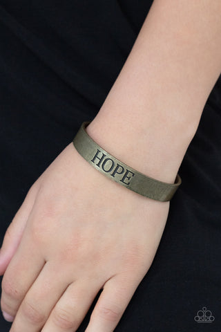 Hope Makes The World Go Round - Brass Bracelet - Paparazzi Accessories  The center of a rustic brass cuff is stamped in the word, "Hope," for an inspirational look.  Sold as one individual bracelet.  New Kit