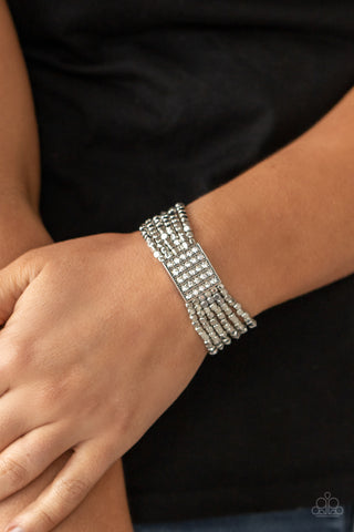 Star-Studded Showcase - White - Paparazzi Accessories Held in place by a square centerpiece encrusted in row after row of dazzling rhinestones, a dainty collection of silver cube beads are threaded along stretchy bands around the wrist, creating shimmery layers.  Sold as one individual bracelet.  New Kit