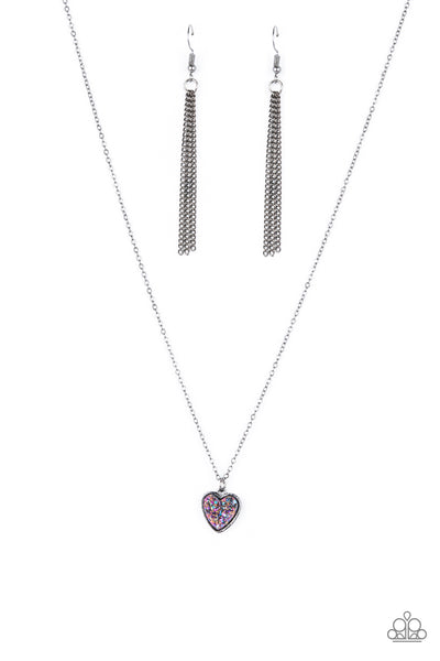 Pitter-Patter, Goes My Heart - Purple Necklace - Paparazzi Accessories A lovely gunmetal heart frame, encrusted with a glittery faux druzy purple stone creates a fun 3D pendant that falls below the collar from a dainty gunmetal chain. Features an adjustable clasp closure.  Sold as one individual necklace. Includes one pair of matching earrings.  New Kit