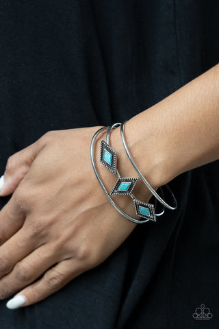 Desert Diamondback - Blue Cuff Bracelet - Paparazzi Accessories Featuring turquoise stones, a trio of diamond shaped antiqued silver studded frames, line up across the center of layered silver bands creating a striking display atop a silver cuff.  Sold as one individual bracelet.  New Kit