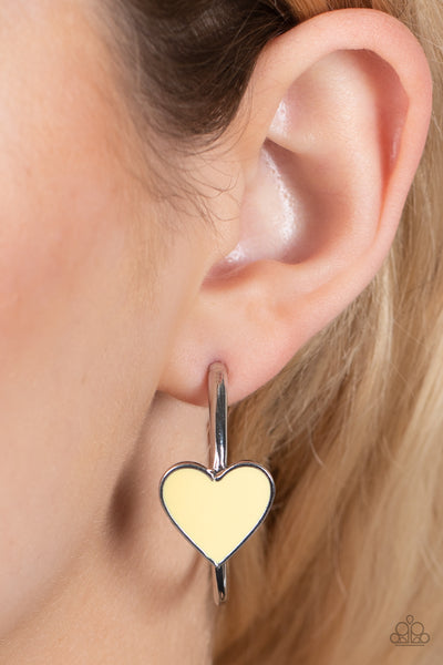 Kiss Up - Yellow Hoop Earrings - Paparazzi Accessories A charming Illuminating heart adorns the front of a classic silver hoop resulting in a whimsical fashion. Earring attaches to a standard post fitting. Hoop measures approximately 1 1/4" in diameter.  Sold as one pair of hoop earrings.  New Kit