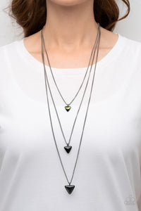 Follow the LUSTER - Black Necklace - Paparazzi Accessories Glassy iridescent, black, and smoky triangular gems gradually increase in size as they swing from the bottoms of extended gunmetal chains, layering into an edgy shimmer across the chest. Features an adjustable clasp closure.  Sold as one individual necklace. Includes one pair of matching earrings.