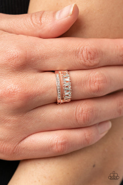 Fractal Fascination - Rose Gold Ring - Paparazzi Accessories Infused with a timeless band of white rhinestones, a dainty collection of trapezoidal cut white rhinestones staggers across the finger for a glamorously layered look. Features a dainty stretchy band for a flexible fit.  Sold as one individual ring.