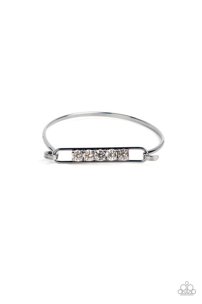 In CHARMS Way - Black Bangle Bracelet - Paparazzi Accessories Encased in gunmetal square fittings, a row of glassy white rhinestones are fitted in place along an airy gunmetal frame that hinges to the center of a bangle-like bracelet for a timeless finish. Features a hinged closure.  Sold as one individual bracelet.