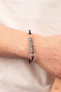 In CHARMS Way - Black Bangle Bracelet - Paparazzi Accessories Encased in gunmetal square fittings, a row of glassy white rhinestones are fitted in place along an airy gunmetal frame that hinges to the center of a bangle-like bracelet for a timeless finish. Features a hinged closure.  Sold as one individual bracelet.