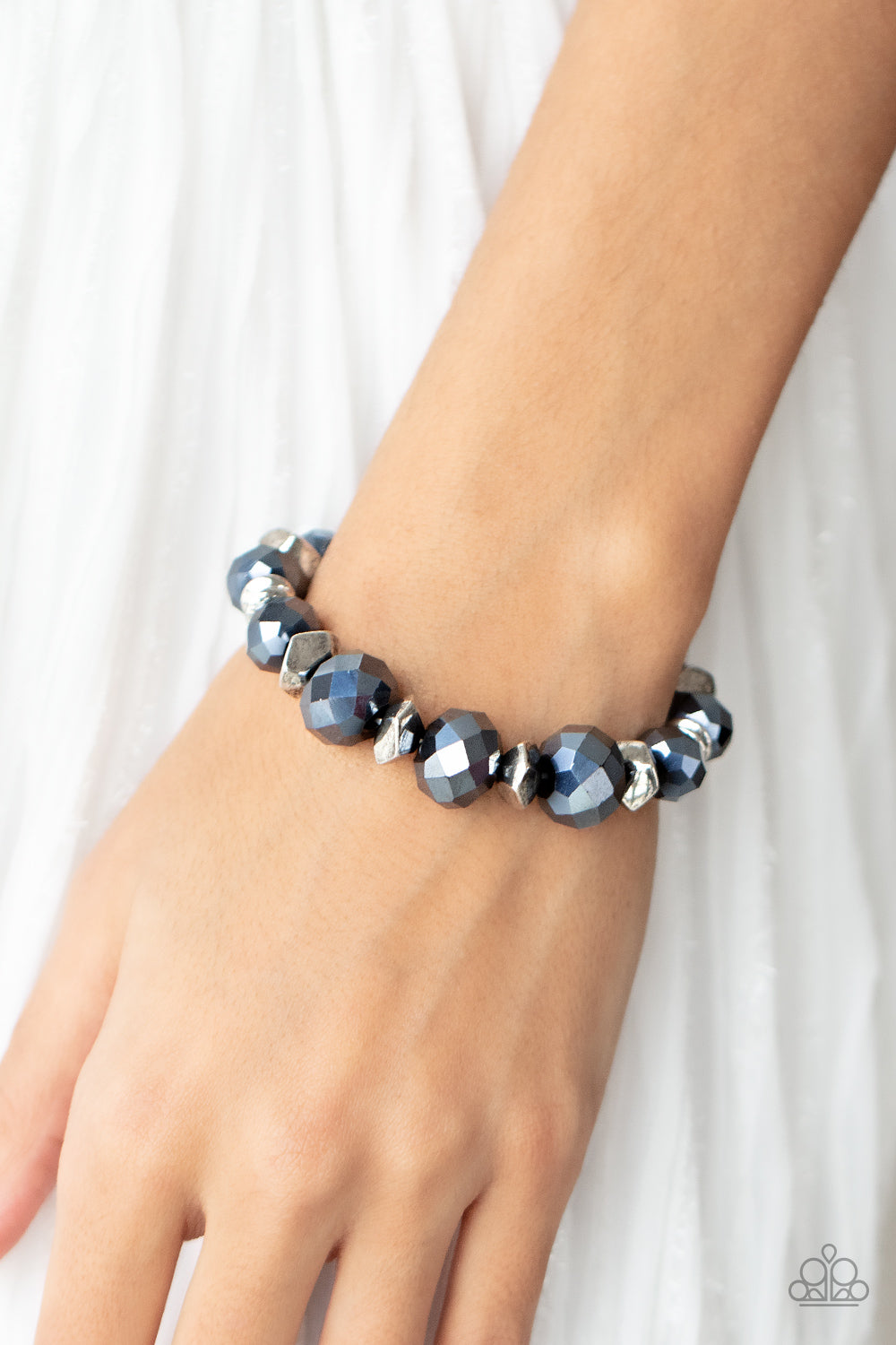 Astral Auras - Blue Bracelet - Paparazzi Accessories Separated by silver discs and faceted silver accents, faceted blue crystal-like gems are threaded along stretchy bands around the wrist for a stellar statement.  Sold as one individual bracelet.   Get The Complete Look! Necklace: "Cosmic Cadence - Blue" (Sold Separately)  New Kit