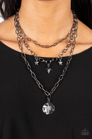 Under the Northern Lights - Black Necklace - Paparazzi Accessories Three gritty gunmetal chains layer down the chest. Flanked by a pair of hammered gunmetal stars, a white rhinestone dotted star swings from the centermost chain above a hammered gunmetal frame twinkling with a white rhinestone dotted star design for a stellar finish. Features an adjustable clasp closure.  Sold as one individual necklace. Includes one pair of matching earrings.